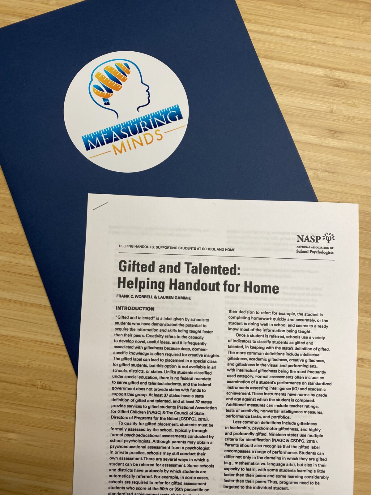 A blue folder with the logo of Measuring Minds on it, next to a document titled "Gifted and Talented: Helping Handout for Home" from the National Association of School Psychologists.